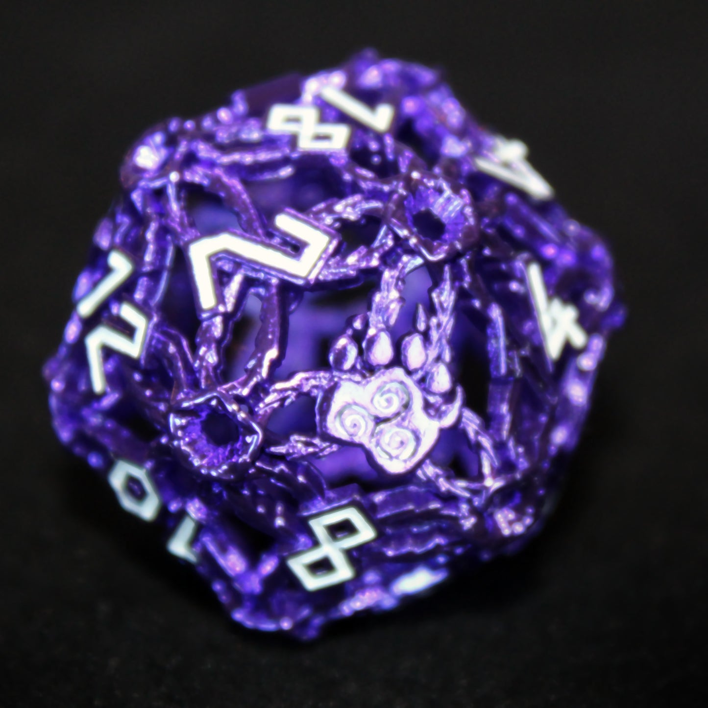 Closeup of a purple druid-inspired hollow metal twenty-sided die with white numbers and a glyph-covered paw in place of the high number on a black background