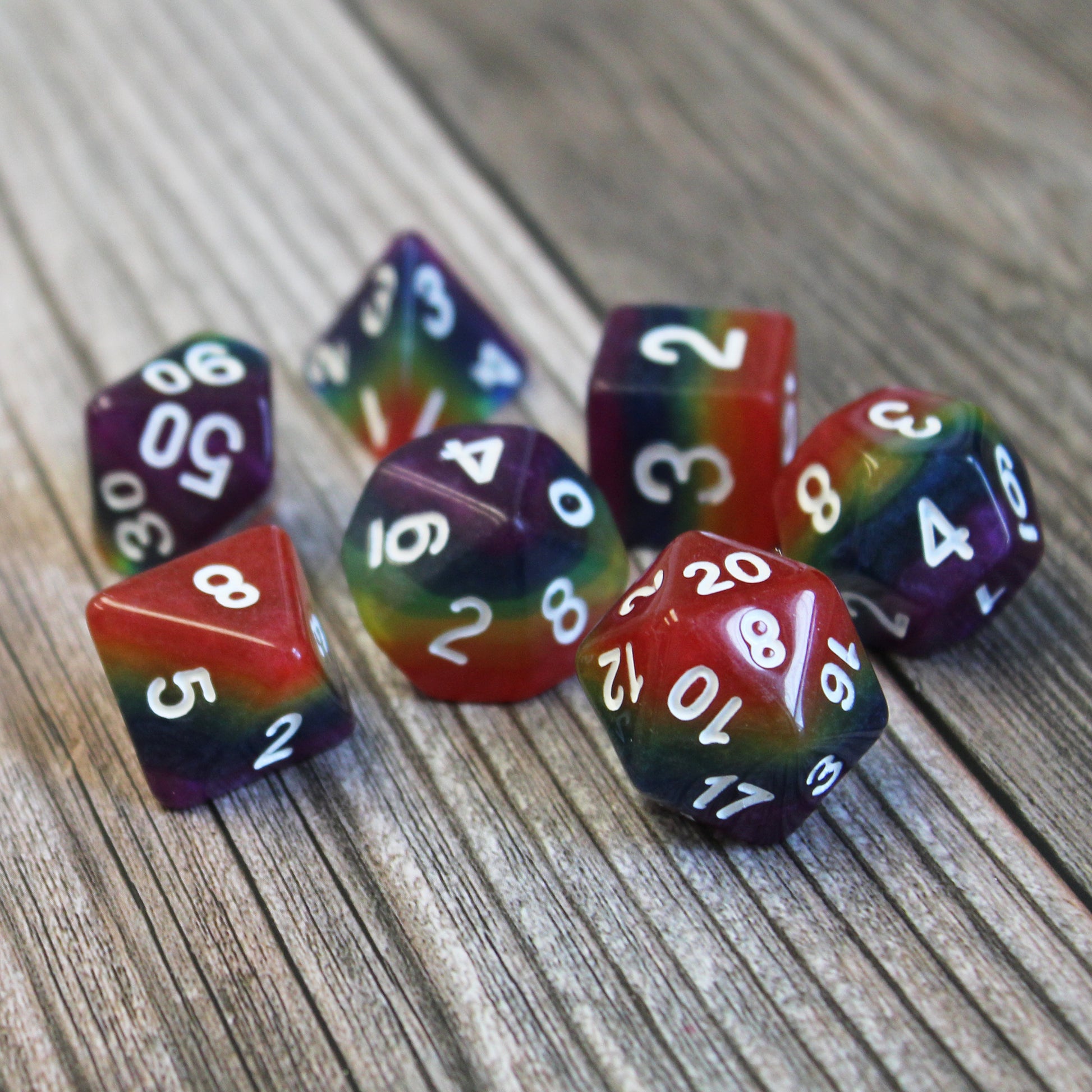rainbow rpg dice on wood with white numbers
