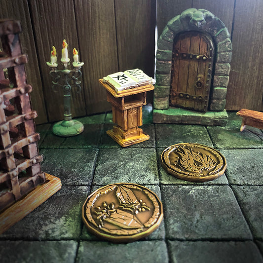 Two golden sorcerer character tokens in a play setting inside of a room with a dais and tome, standing candelabra, and metal cage.