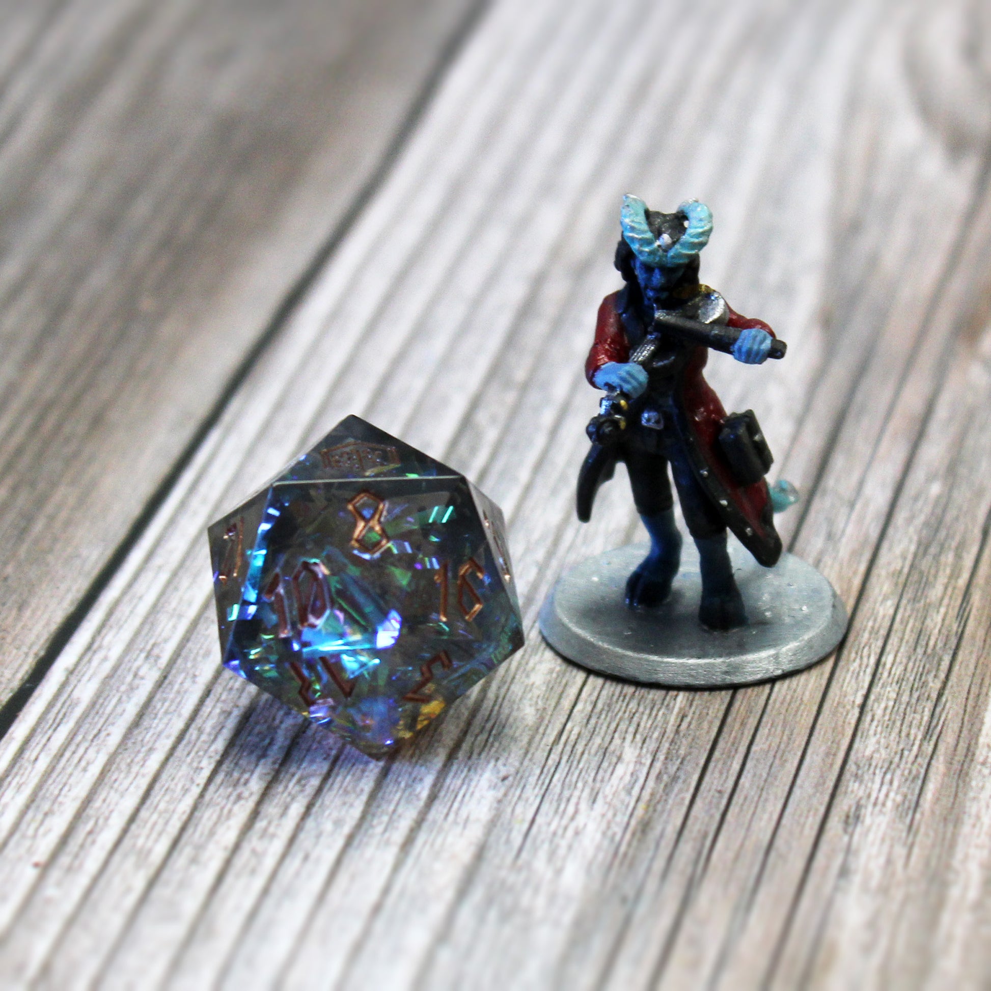 StarGlow Smoke resin dice set placed next to a D&D miniature, with iridescent flashes of color and sharp-edged design for tabletop gameplay.