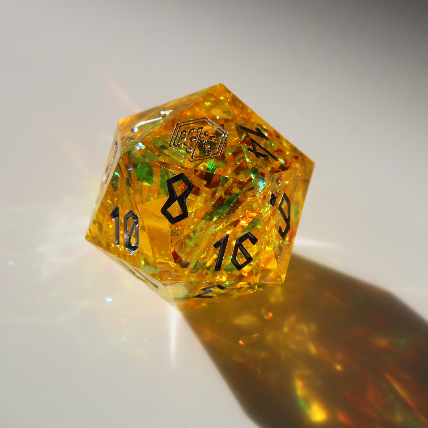 Close-up of the StarGlow Yellow D20 under bright light, showcasing the translucent resin and iridescent colors that shimmer in green and gold.