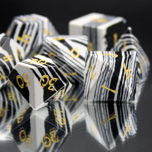 Close Up of Black and White Striped Dice with Gold Numbering on a Mirrored Background.