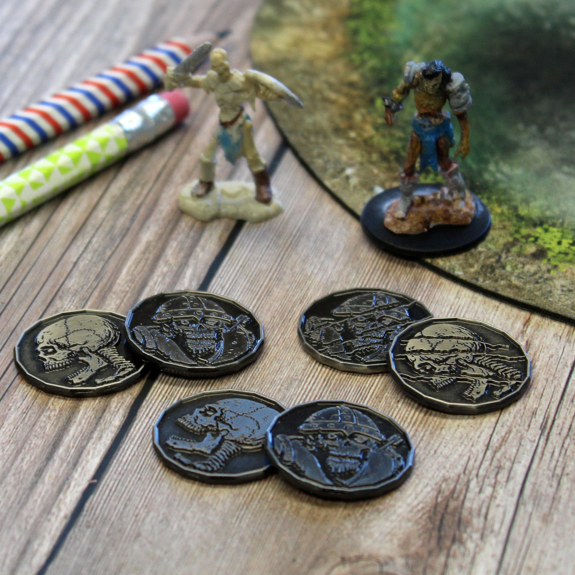 Six Skeleton and Zombie Tokens, with Heads and Tails Sides Showing, Pictured Next to Mini Figures.
