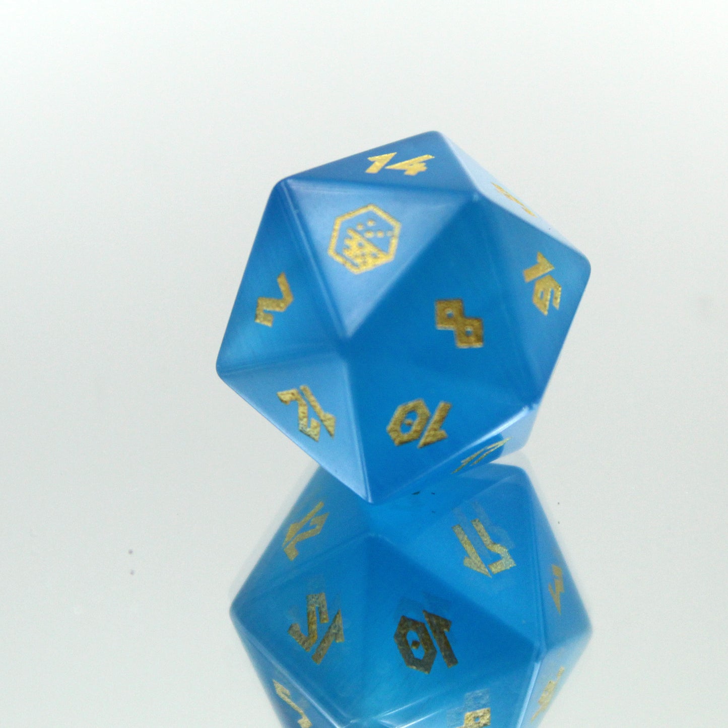 Showcased Cat's Eye Blue D20, displaying the smooth ombre effect of deep blue glass with gold numbering.