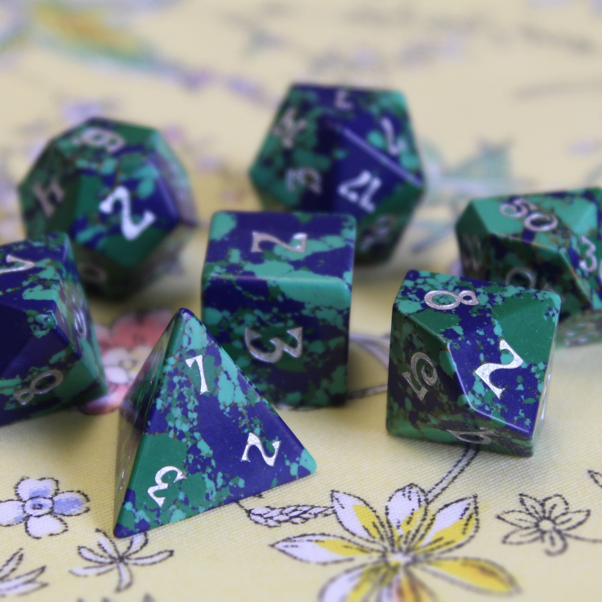 Gaia Dice Set displayed on a table, featuring easy-to-read white ink on deep greens and blues.