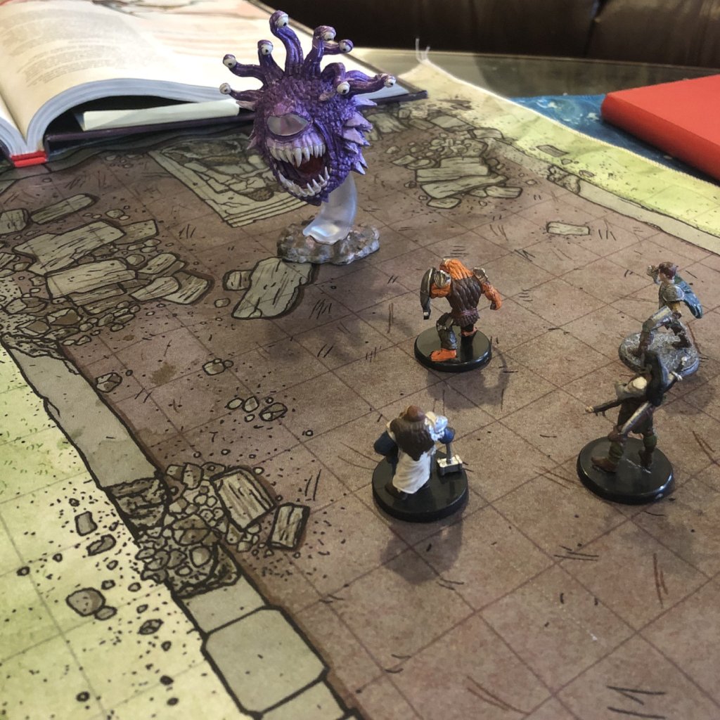 Photo of a temple battle map with miniatures scattered on it in a battle formation